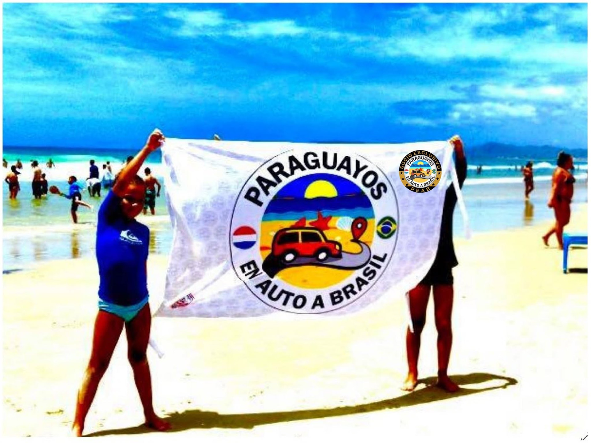 Socios del grupo Paraguayos en Auto a Brasil con la bandera del club en una playa de Brasil